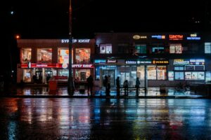 A city street at night with lights reflecting off of the wet pavement